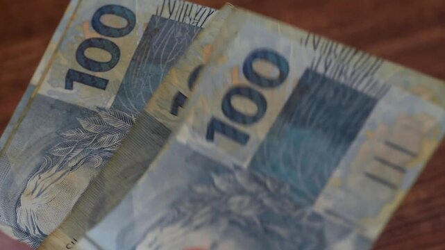 Counting R$100 bills. Brazilian currency (Real) being counted. Concept of economy, debts, purchases, financial transactions.