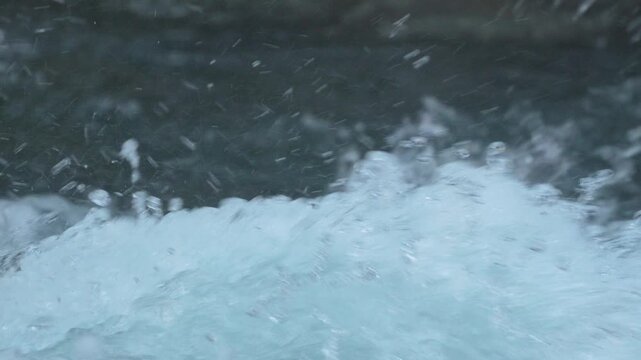 River water rushing and splashing over rocks in a mountain stream with white foam and bubbles in 120fps 4K Slow Motion