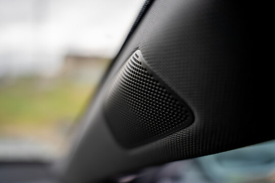 Close up of a built in car speaker tweeter integrated into the front A pillar trim, showcasing modern automotive audio system design and interior plastic texture.