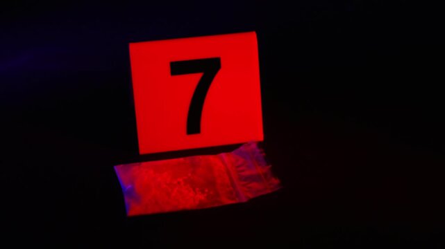 Fentanyl bag near evidence marker. Educational concept of drug bust trafficking for sale at night club or party location. Opioids and meth smuggling operation seizure. Contraband and criminal activity