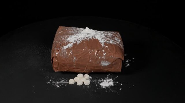 Brown packages filled with drugs and wrapped in duct tape to avoid k9 dog detection at border. Educational concept of drugs in powder for pill pressing and distribution.