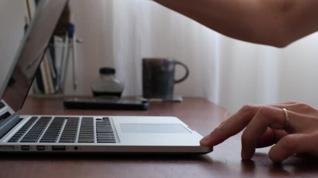 Opening a laptop and using touchpad at home office desk
自宅のデスクでノートPCを開いてタッチパッドを操作する手元