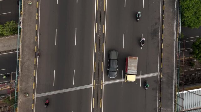 Color graded top down aerial view of vehicles driving on a multi lane city highway bridge road