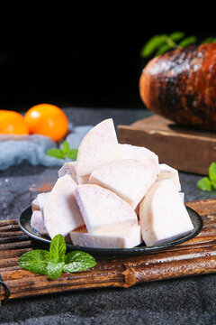 Fresh Sliced Taro Root Lipu from Guangxi China on Rustic Wooden Board with Mint Garnish
