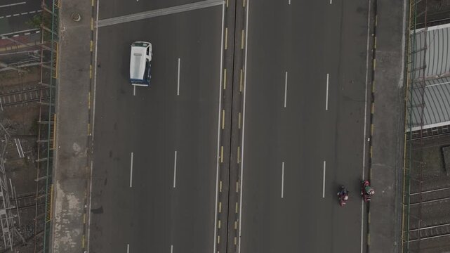 Aerial top down view of a highway bridge with moving motorcycles and a white minivan