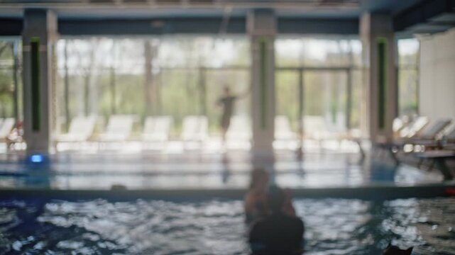Blurred view of children swimming assisted by instructors during swimming lessons