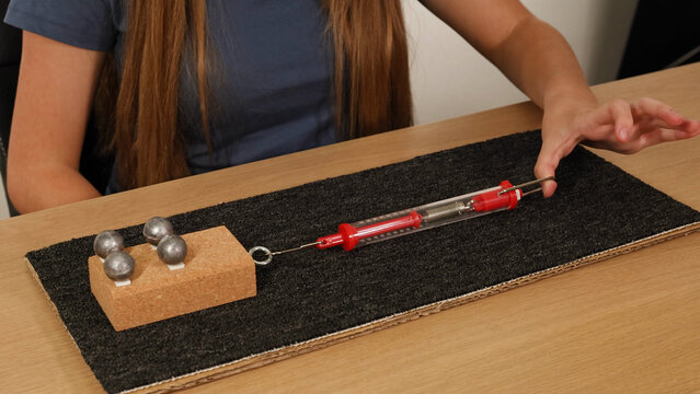 Physics Experiment Measuring Friction on Carpet with Spring Scale and Weights