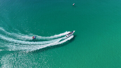 Fototapeta premium Aerial View of a Speedboat Towing an Inflatable Tube in Turquoise Water