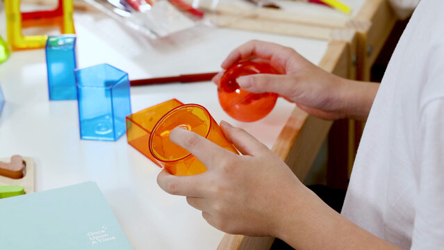 Child Holding Translucent Orange Geometric Solids During Math Lesson