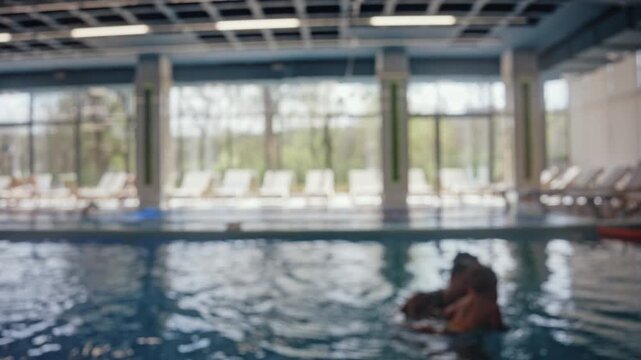 Blurred view of children swimming assisted by instructors during swimming lessons