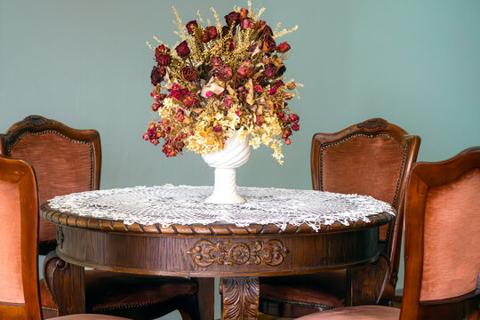 Antique dining table with chairs and vase of dried flowers