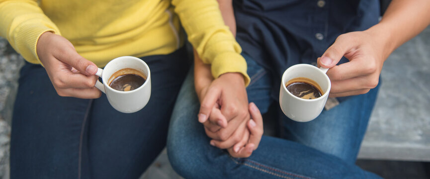 Banner Close up Hands holding coffee cup. Couple lover drinking black cup of coffee together. Banner Top view hands two people happy cafe coffee shop. Espresso shot with copy space