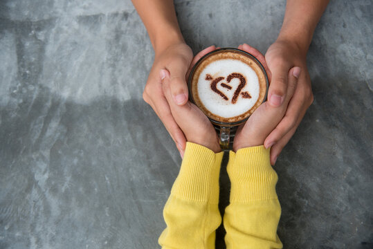 Close up Hands holding coffee cup. Couple lover drinking cup of coffee latte art together. Top view hands two people happy in cafe coffee shop. Espresso shot Young couple happy date relaxing in cafe