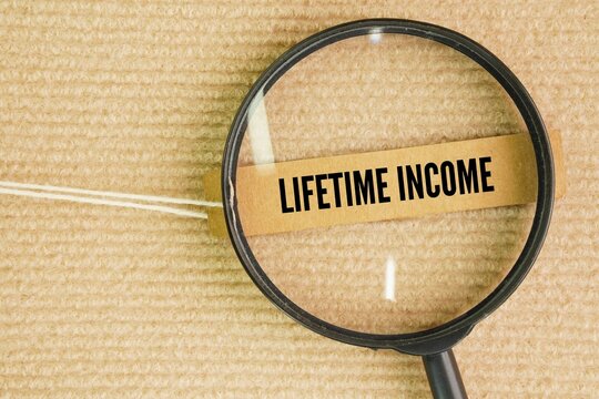 A magnifying glass and a paper tag with the words lifetime income. steady, predictable stream of payments designed to last for the rest of your life. It is typically used in retirement planning