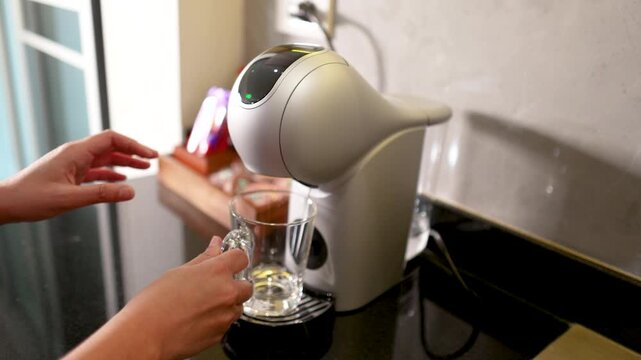 Person Preparing a Modern Capsule Coffee Machine on a Kitchen Counter