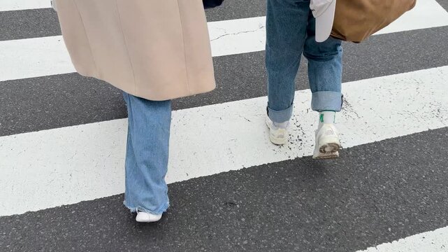 Pedestrians in Blue Jeans Walking Across a Zebra Crosswalk in Tokyo Japan