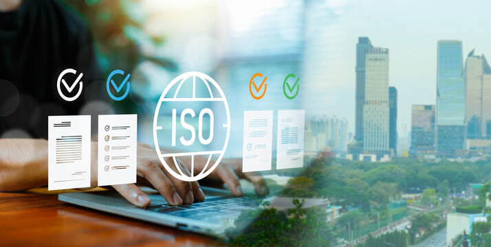 Businessman working on laptop with ISO certification icon and city background. Quality management system, international standard compliance, business control and document check concept.