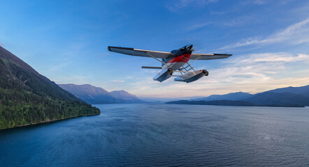Fototapeta premium Seaplane Flying Over Coastal Lake With Mountainous British Columbia Background at Sunset