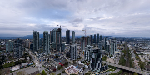 Obraz premium Burnaby Vancouver City Skyline With High-Rise Towers and Construction Cranes Under Overcast Sky