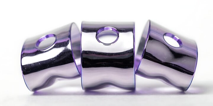 Three shiny metallic cylindrical objects with holes on white background  industrial hardware components