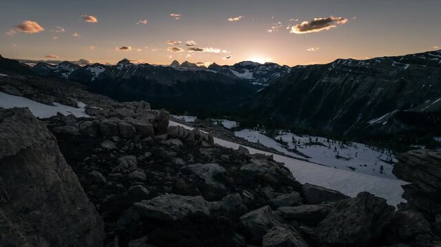 Majestic mountain range bathed in golden sunset light with lingering snow patches