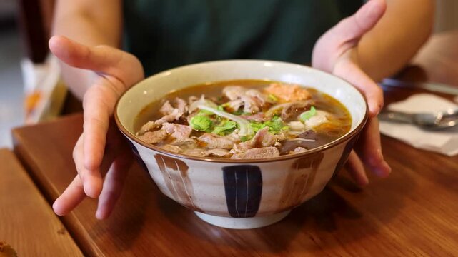 Person Presenting a Large Ceramic Bowl of Vietnamese Bun Cha Noodle Soup