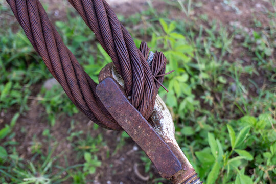 Close up of thick rusty steel wire rope cable and metal hardware over grass
