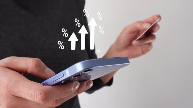 Businesswoman holding a bank card while holding a smartphone with a graphic animation of white arrows rising, surrounded by percentage symbols.