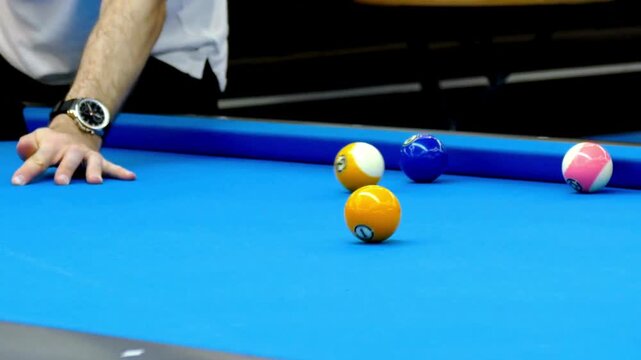 Man playing pool with colorful balls on blue table with cue stick