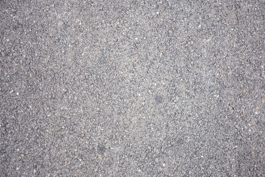 Detailed close-up of rough asphalt surface texture with natural gray tones and gritty urban pattern. Ideal for construction, road backgrounds, industrial textures, and design overlays.