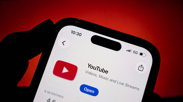 Closeup of a smartphone screen displaying the youtube app page in the app store, with a red background
