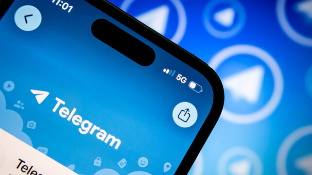 Closeup of a smartphone screen displaying the telegram messaging app logo and interface, with a blurred telegram background pattern