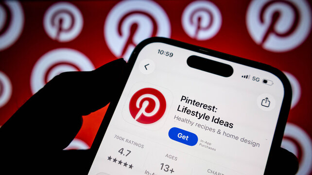 Closeup of a smartphone screen displaying the pinterest app store page with the download button visible, held in hand against a branded background