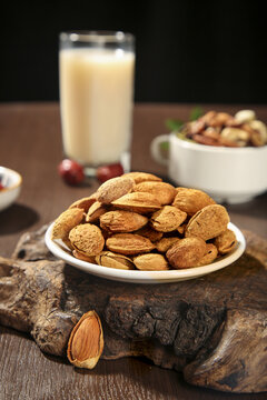 Fresh Almonds and Assorted Nuts with Creamy Milk Beverage on Rustic Wood Background