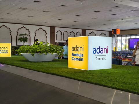 Adani Cement display at airport terminal highlights conglomerate enterprises linked to ports, infrastructure and industry amid quarterly results, profit and loss discussions in Indias business sector.