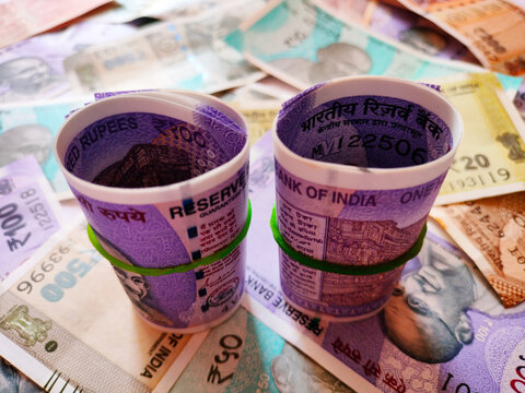 Indian Rupee Notes Composition with Rolled Hundred Rupee Banknote