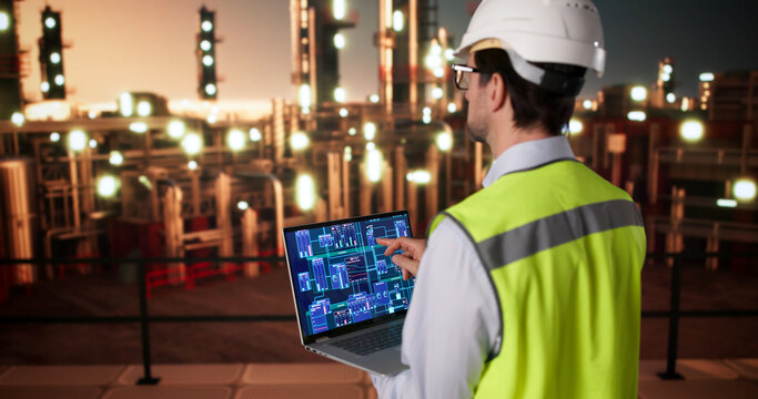 Engineer Monitors Refinery Data On Laptop