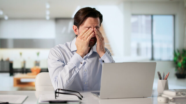 Tired Man Rubbing Sore Eye While Working