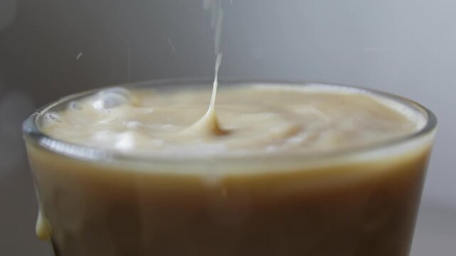 Milk drop to coffee cup and splashing up. Slow motion beverage background
