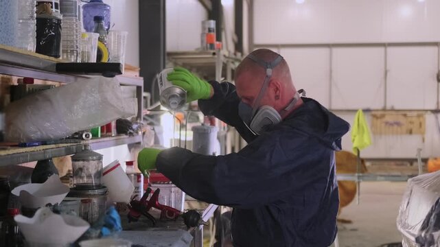 Auto body painter measuring lacquer and mixing ingredients at workshop shelf, preparing clear coat materials for insured vehicle repair, collision refinishing and paint restoration.