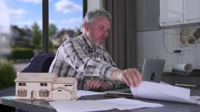 Engineer talking during video call, reviewing documents and working from home office with laptop and architectural models for remote planning sessions. video conference engineer