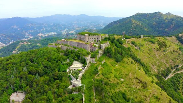 Genoa, Italy. Forte Sperone, a massive stone fortress with grass-covered ramparts, Drone footage over the Ligurian hills and distant coastline. Drone footage, Point of interest