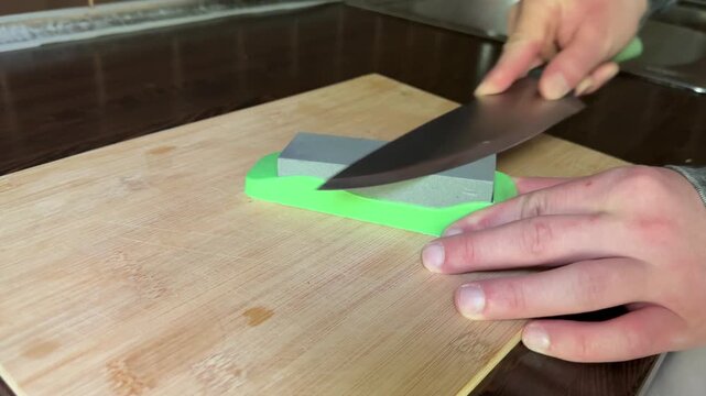 Sharpening kitchen knives on whetstone close up