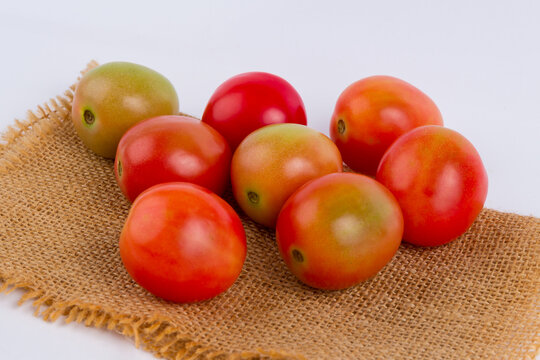 Fresh red tomatoes on burlap sack cloth isolated on white background.