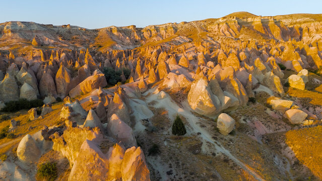 Goreme, Nevsehir, Turkey. Inspiring aerial view of Devrent Valley with magical rock formations and golden sunset colors.. Aerial View