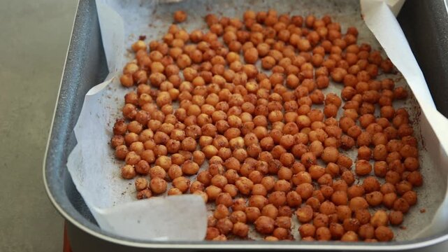 Close-up of crispy, seasoned baked chickpeas cooling on a metal baking tray right out of the oven