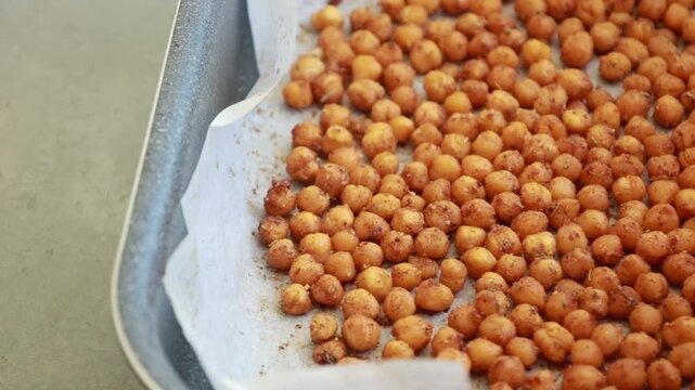 Close-up of crispy, seasoned baked chickpeas cooling on a metal baking tray right out of the oven