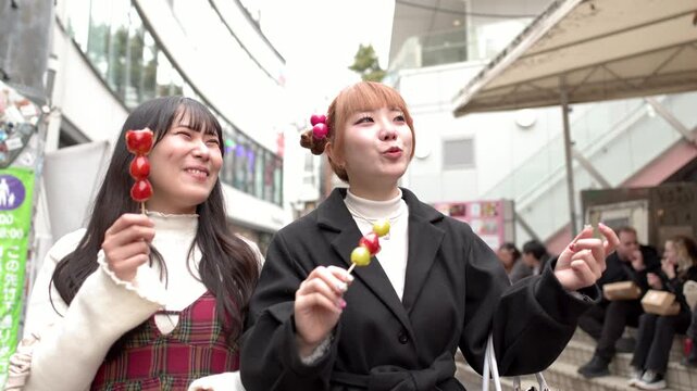 Two Young Japanese Women Enjoying Candied Fruit Skewers in Tokyo
