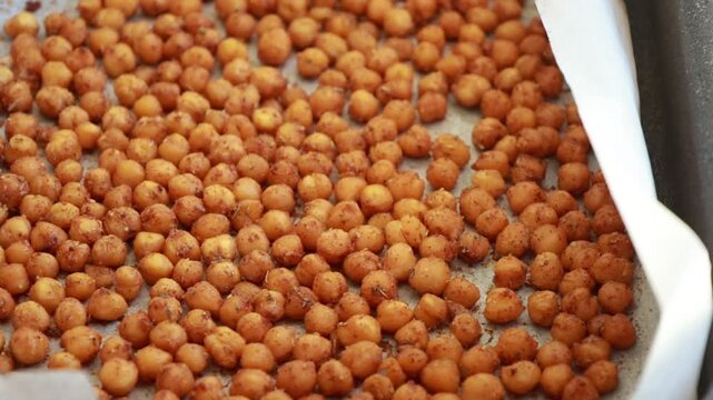 Close-up of crispy, seasoned baked chickpeas cooling on a metal baking tray right out of the oven
