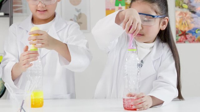 Two Asian Children in Lab Coats Perform Science Experiment with Balloons